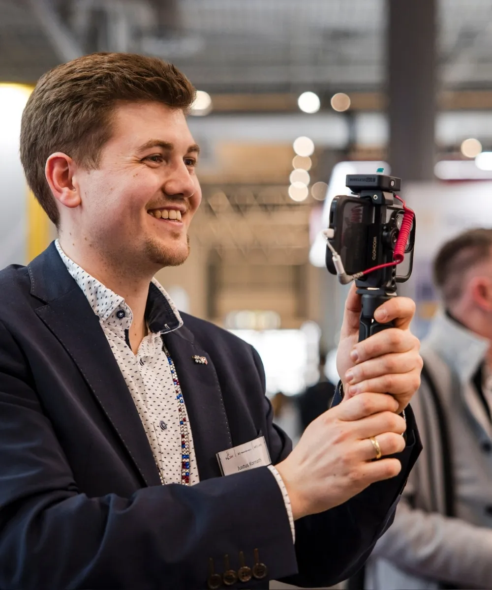Justus Kornath dreht mit Smartphone und Handgriff einen Messefilm